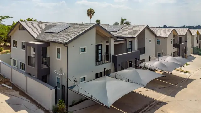 Double-storey cluster homes with shade-net carports along a shared driveway