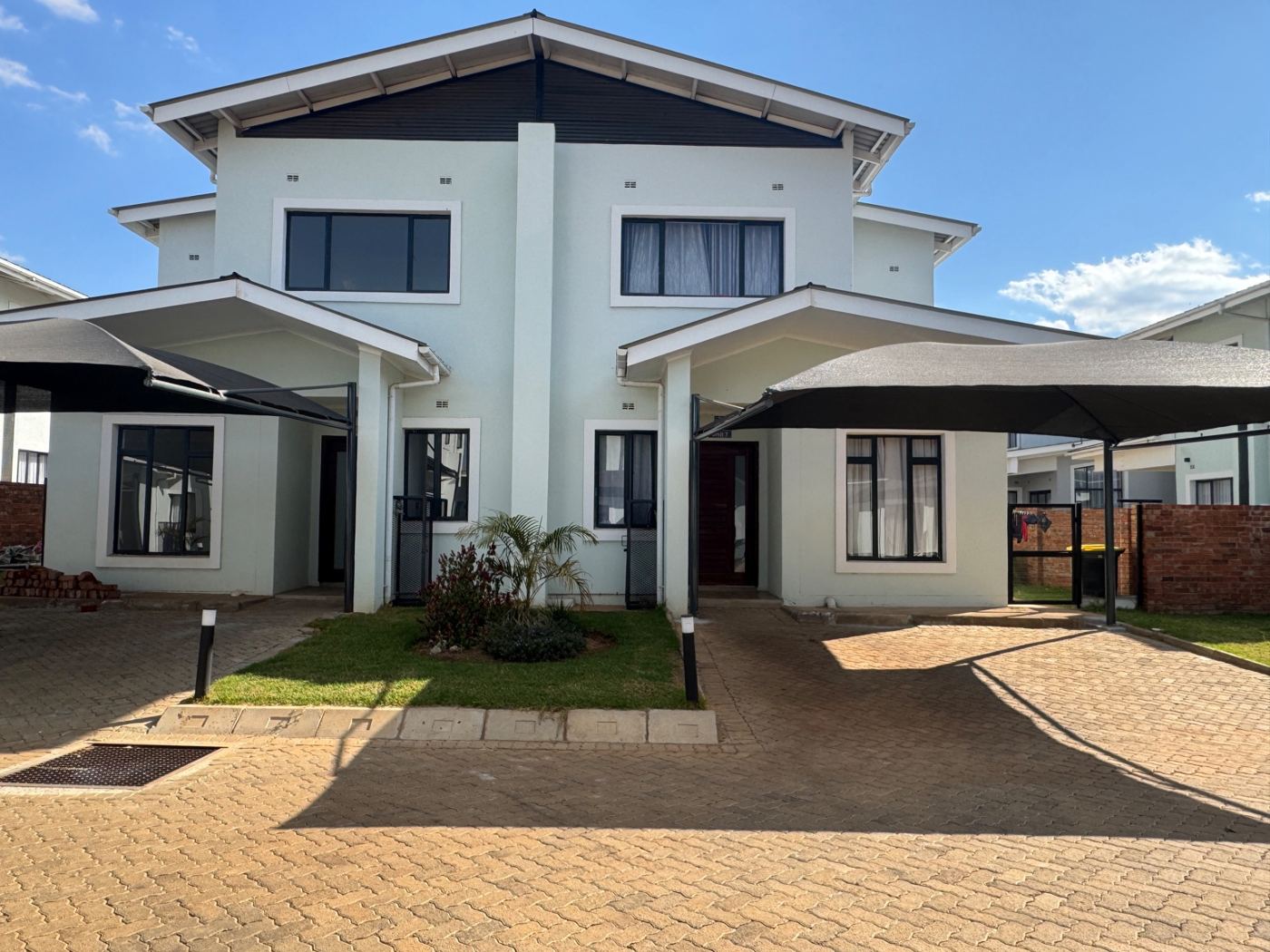 Pair of double-storey cluster units with paved driveway, carports and front garden