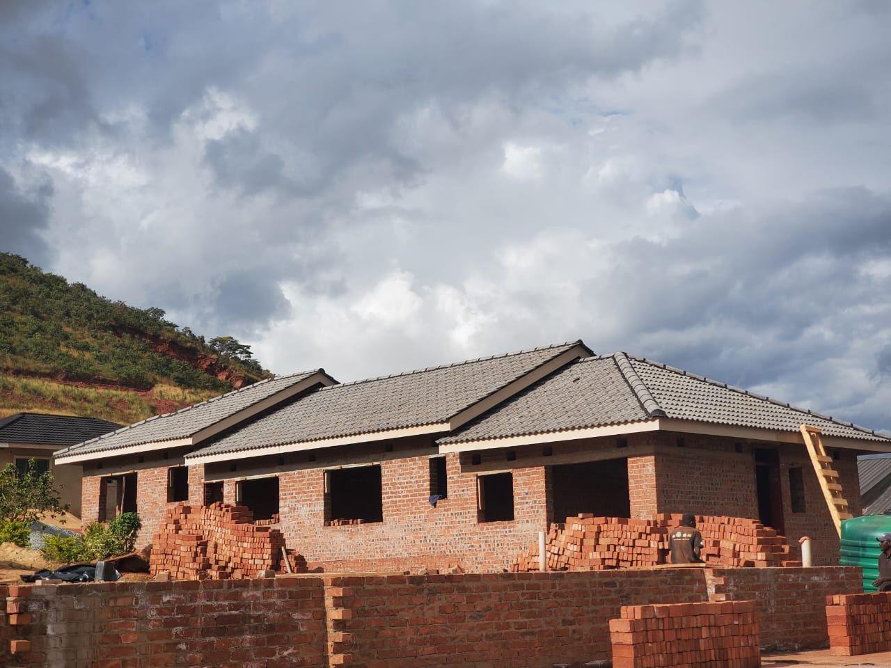 Brick house with a tiled roof, bricks stacked for the boundary wall